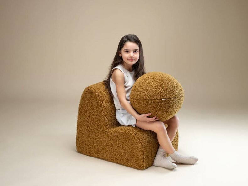 Wigiwama Kinderkissen Ball Maple in sanftem Maple Farbton von einem Mädchen gehalten