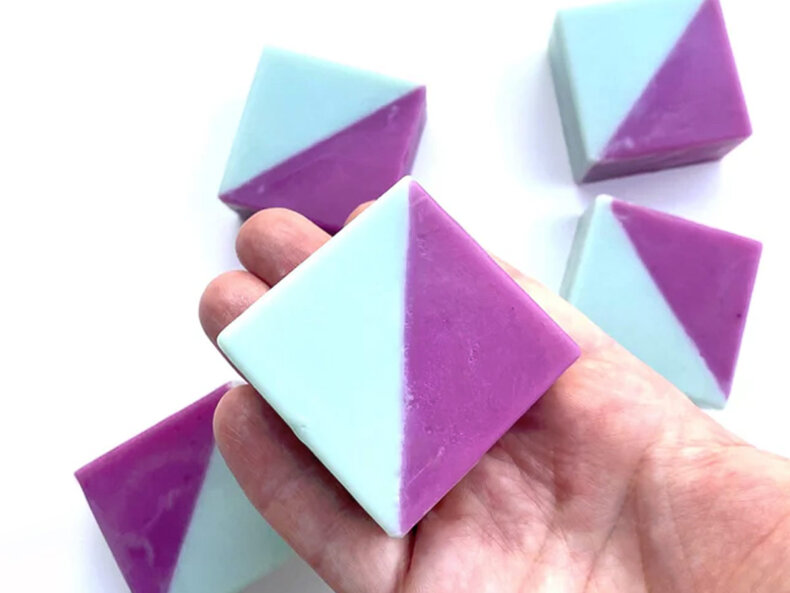 Zweifarbige geometrische Seife „RONJA – Limone & Rosmarin“ in Türkis und Lila, handgemacht und vegan; kleine rechteckige 40-g-Seife mit frischem Zitrus-Rosmarin-Duft auf heller Oberfläche.