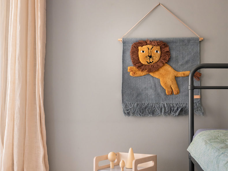 Der Wandteppich Kinderzimmer Jumping Lion von OYOY Mini hängt an einer Wand eines Kinderzimmers.
