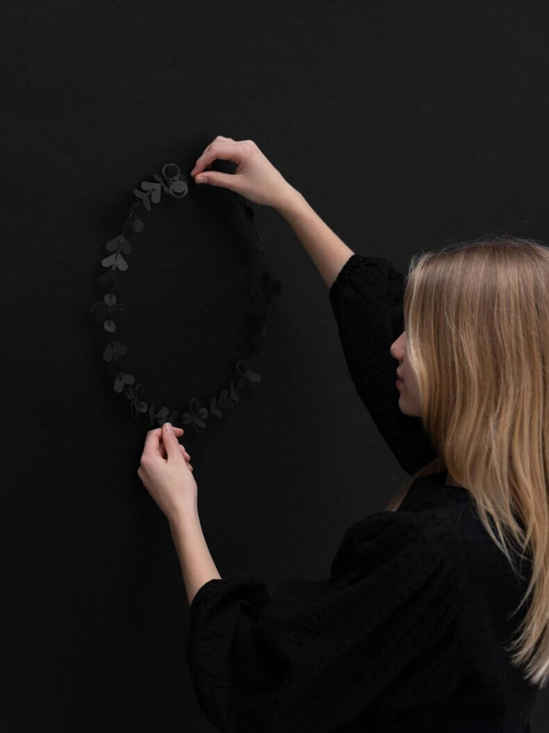 Frau hängt die schwarze Papiergirlande FOLK ornaments von Jurianne Matter an die Wand.